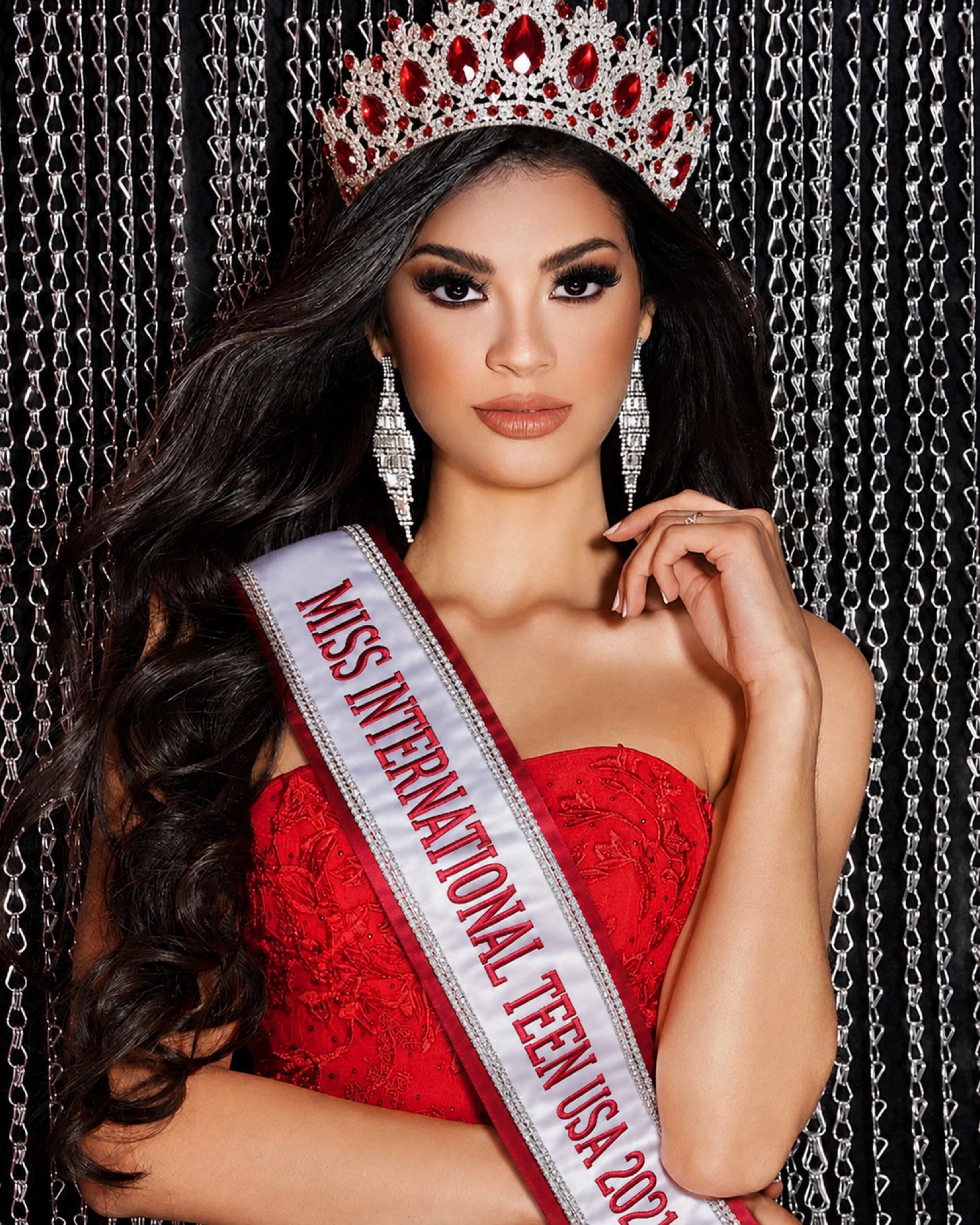 Crowned pageant titleholder in a red gown and crown, coached by Jeins Castañeda